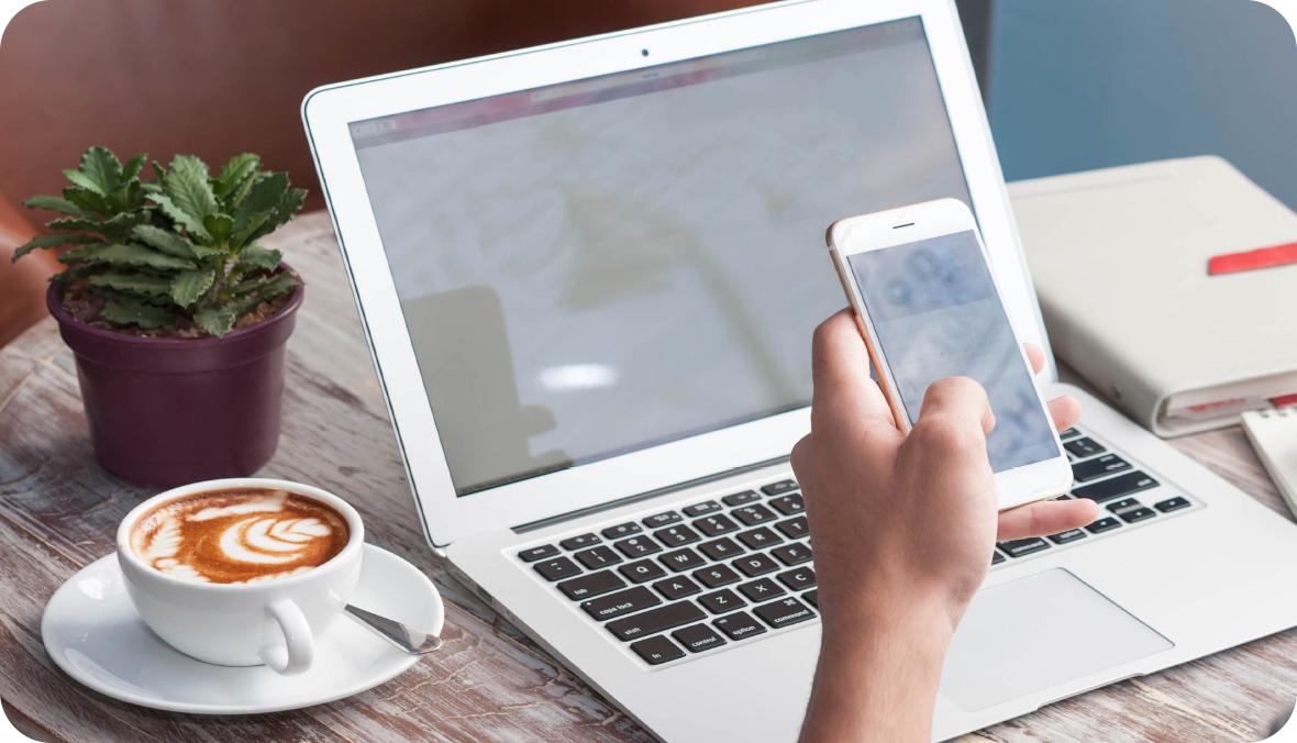 overhead view of a coffee cup, keyboard, notepad on a wooden table top